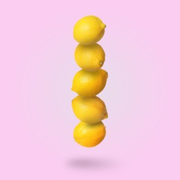 Image of Whole fresh lemons falling on pink background