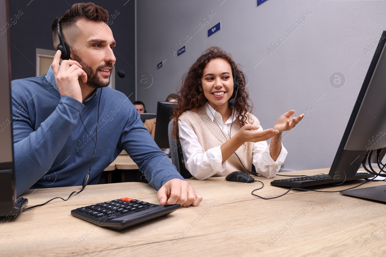 Photo of Call center operators with headsets working in office, low angle view