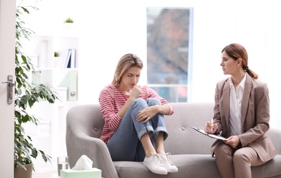 Psychotherapist working with young woman in light office