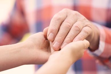 Photo of Young woman holding elderly man hand, closeup. Help service