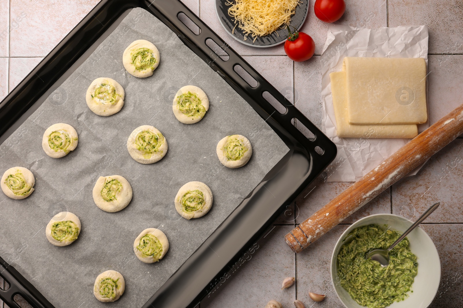 Photo of Raw puff pastry and ingredients on tiled table, flat lay