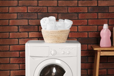 Photo of Washing machine, terry towels and bottle indoors. Laundry room interior design