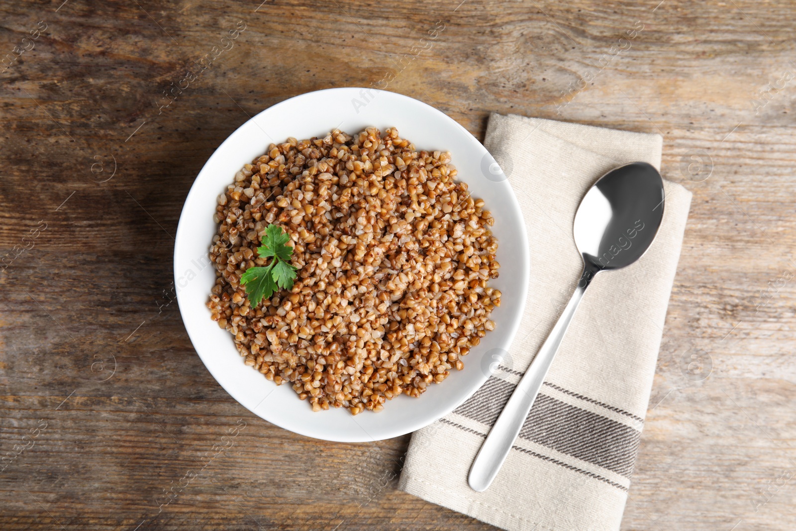 Photo of Flat lay composition with dish of buckwheat porridge served on wooden table