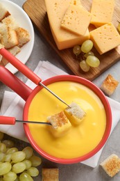 Flat lay composition with pot of tasty cheese fondue on grey table