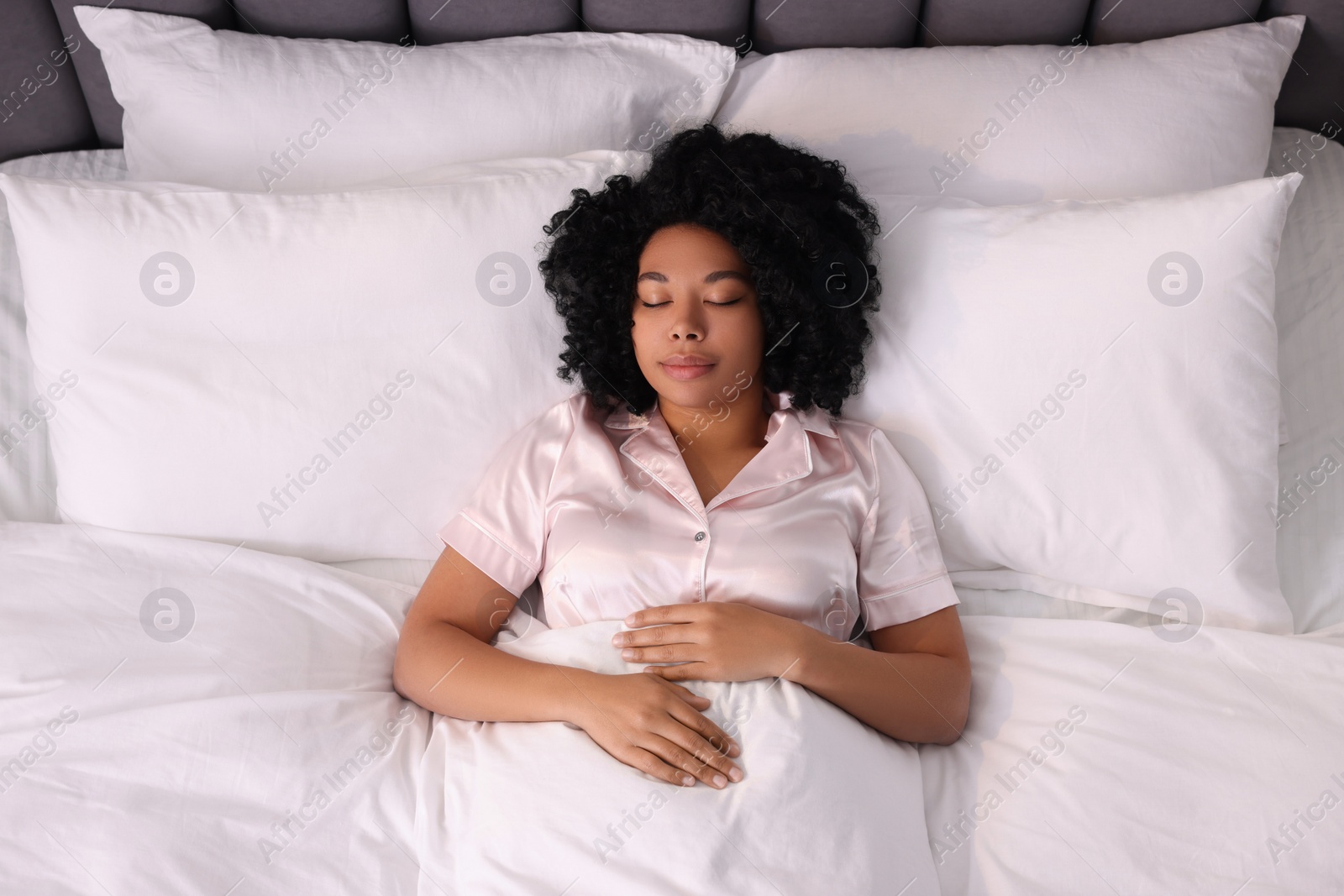 Photo of Beautiful young woman sleeping in soft bed, above view