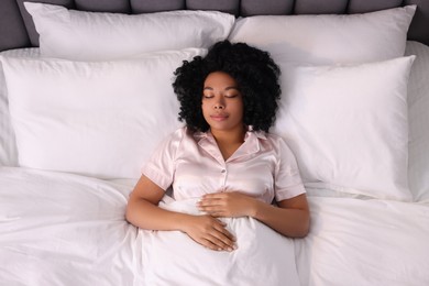 Beautiful young woman sleeping in soft bed, above view