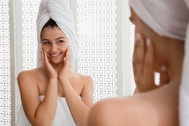 Beautiful teenage girl with towels near mirror in bathroom