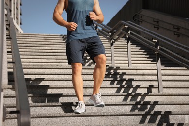 Man running down stairs outdoors on sunny day, closeup