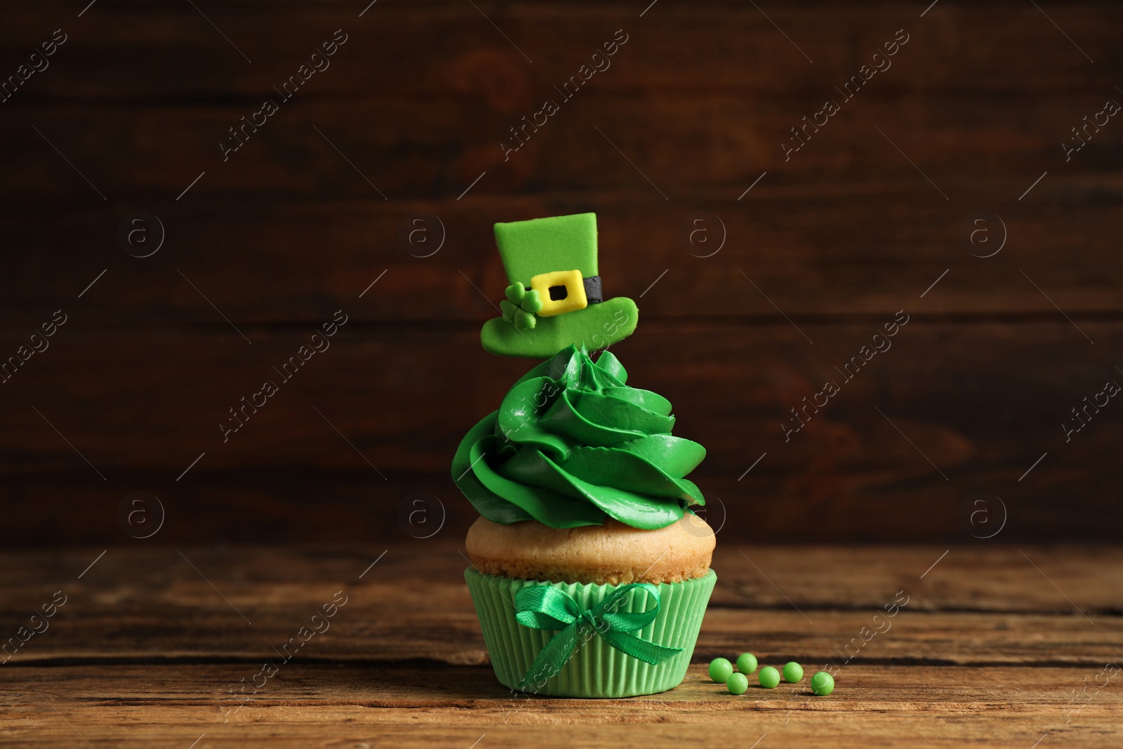 Photo of Delicious decorated cupcake on wooden table. St. Patrick's Day celebration