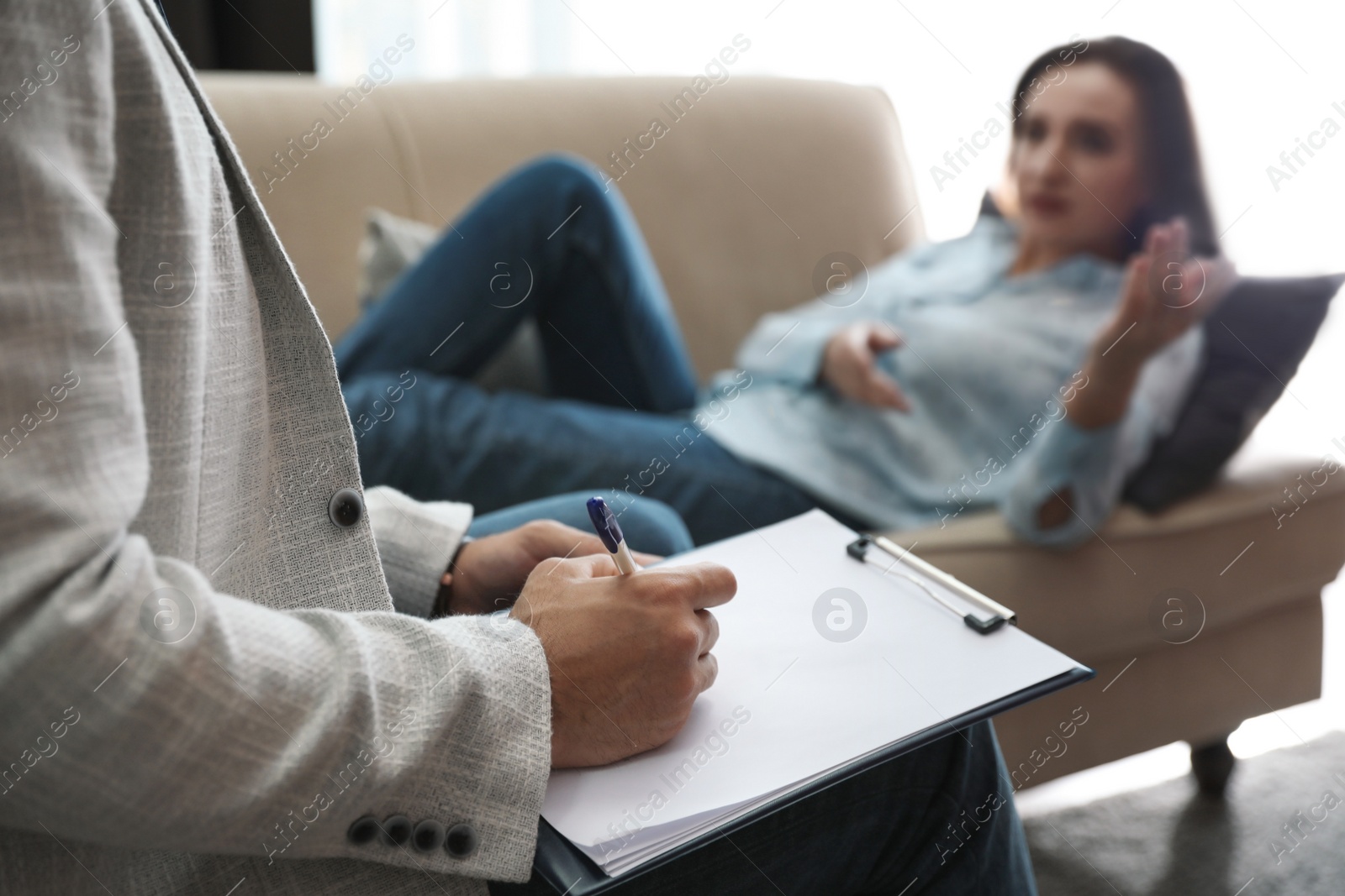 Photo of Professional psychotherapist and patient in office, focus on hands with clipboard