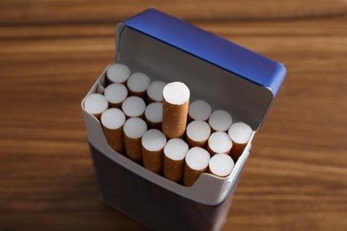 Photo of Pack of cigarettes on wooden table, closeup