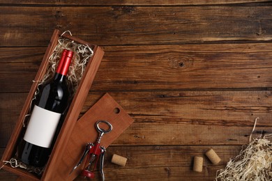 Photo of Box with wine bottle, corkscrew and corks on wooden table, flat lay. Space for text