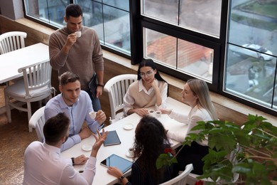 Photo of Group of coworkers having coffee break in cafe