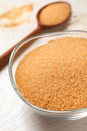 Photo of Brown sugar in bowl on white wooden table, closeup