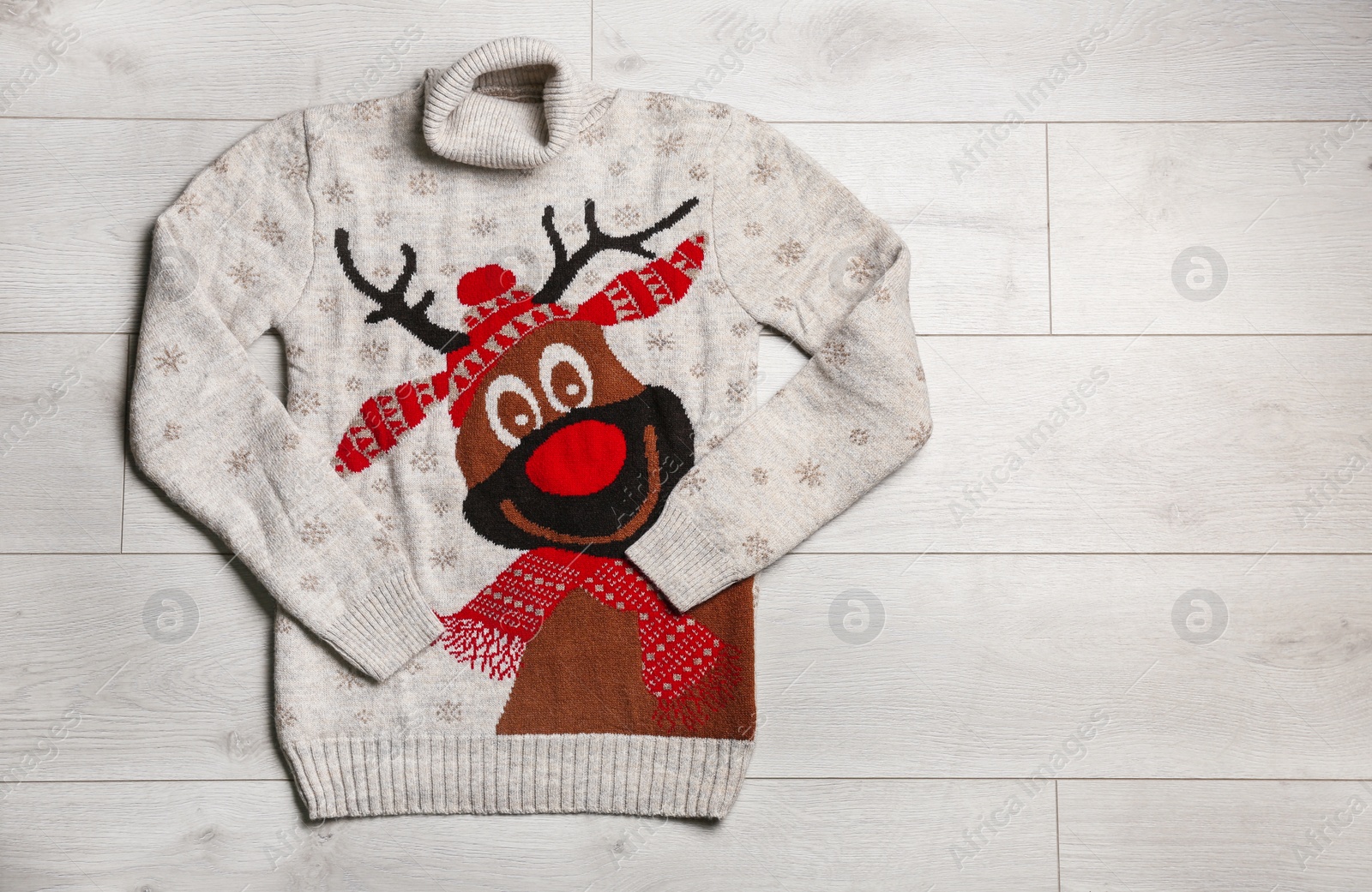 Photo of Warm Christmas sweater on wooden table, top view. Space for text