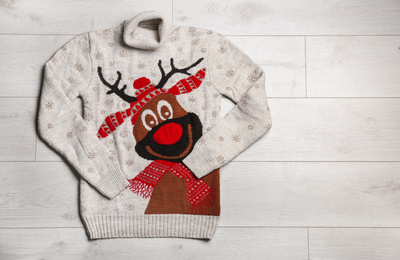 Warm Christmas sweater on wooden table, top view. Space for text