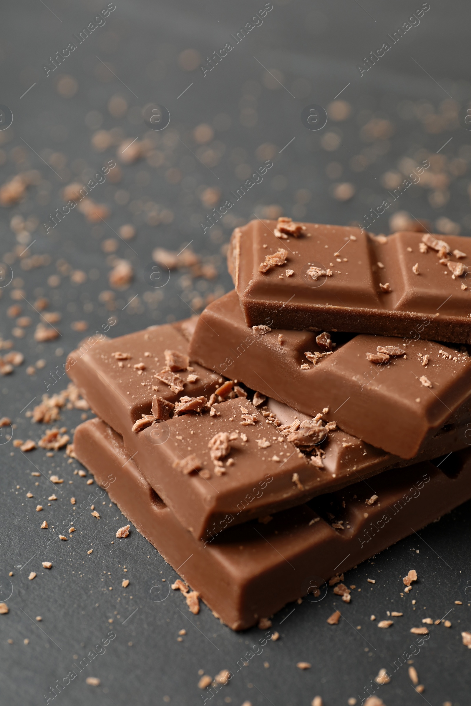 Photo of Pieces of tasty chocolate on grey table, closeup
