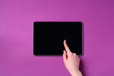 Photo of Online store. Woman using tablet on purple background, top view