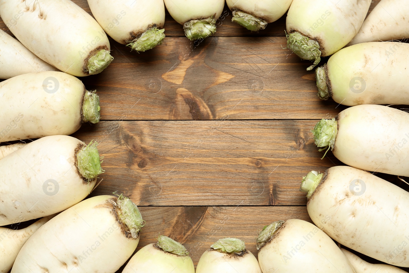 Photo of Frame of white turnips on wooden table, flat lay. Space for text