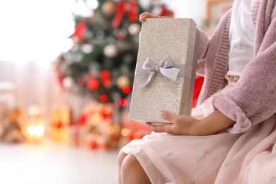 Photo of Cute little child with Christmas gift box at home