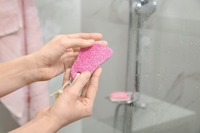 Photo of Woman holding pink pumice stone near shower stall in bathroom, closeup. Space for text