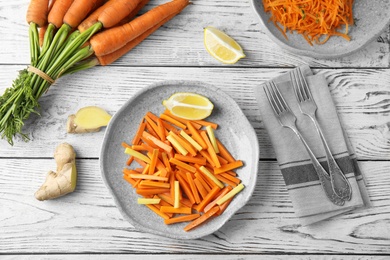 Photo of Plate with tasty carrot salad on wooden table, top view