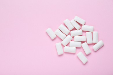 Photo of Tasty white chewing gums on pale pink background, flat lay. Space for text