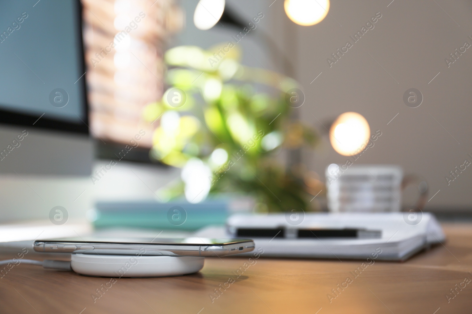 Photo of Modern workplace and smartphone charging with wireless pad