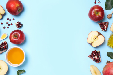 Photo of Honey, apples and pomegranates on light blue background, flat lay with space for text. Rosh Hashanah holiday