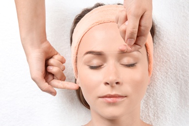 Young woman having eyebrow correction procedure in beauty salon