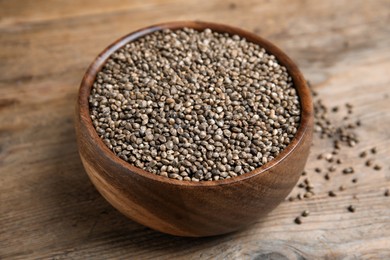 Photo of Bowl with organic hemp seeds on wooden table, closeup