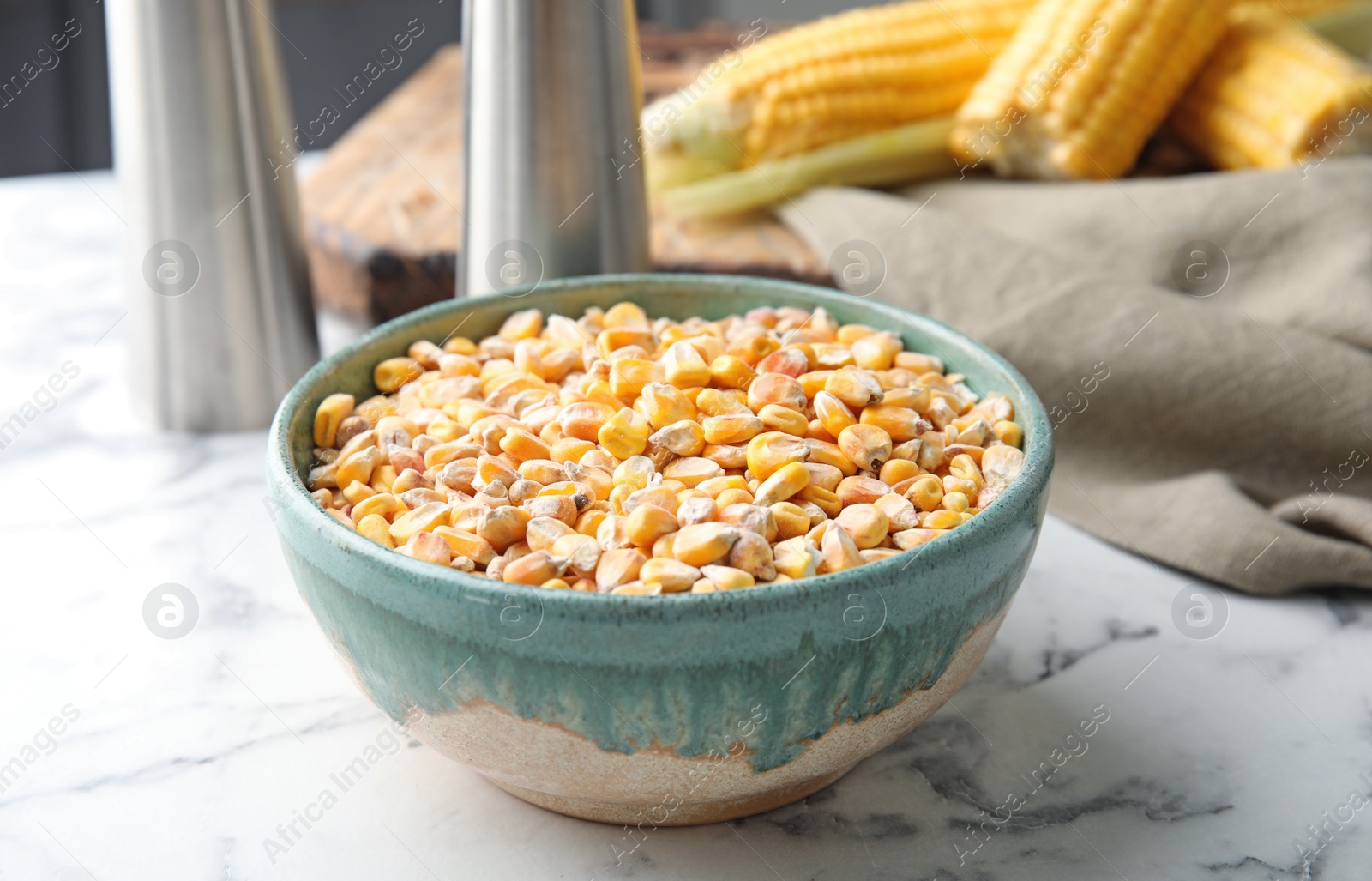 Photo of Bowl with dried corn kernels on marble table