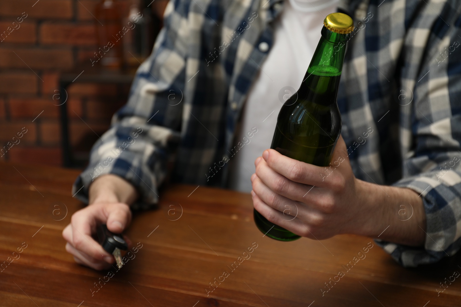 Photo of Man with bottle of beer and car keys at table, closeup. Don't drink and drive concept