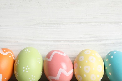 Photo of Colorful painted Easter eggs on wooden background, top view. Space for text