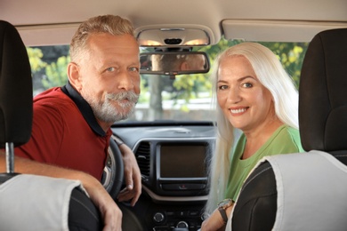 Happy senior couple sitting together in car