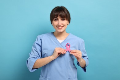 Mammologist with pink ribbon on light blue background. Breast cancer awareness