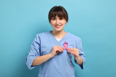 Photo of Mammologist with pink ribbon on light blue background. Breast cancer awareness