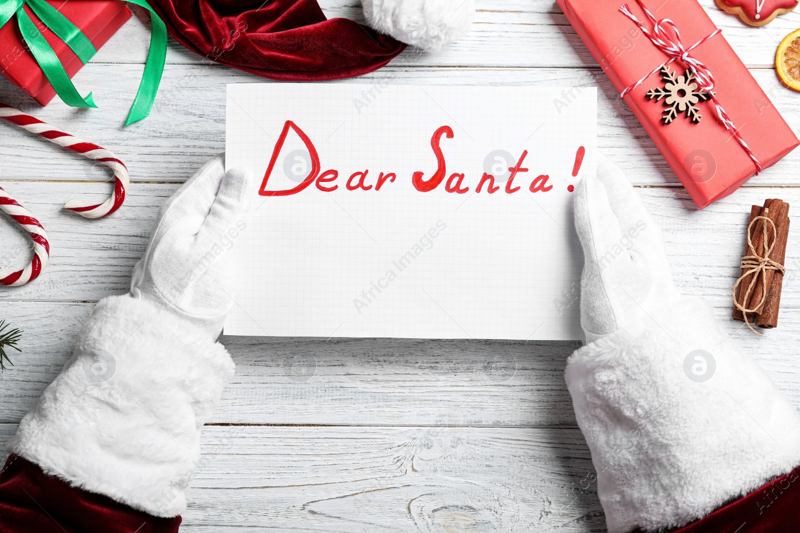 Photo of Santa Claus with letter and Christmas decor at white wooden background, top view