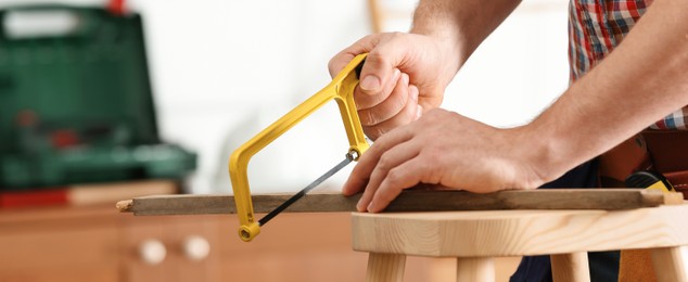 Image of Man working with hand saw indoors, closeup. Banner design