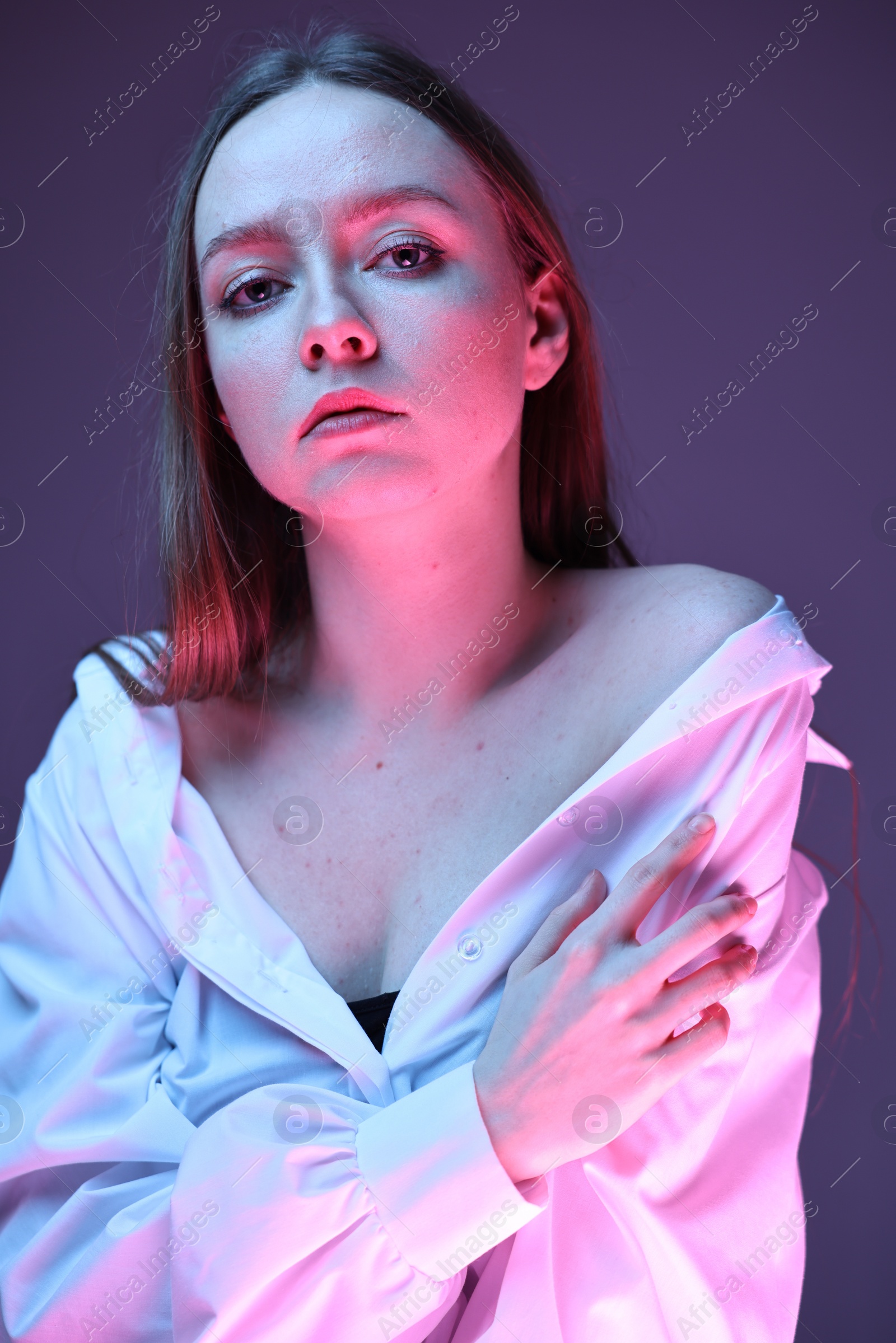 Photo of Fashionable portrait of beautiful young woman on purple background in neon lights