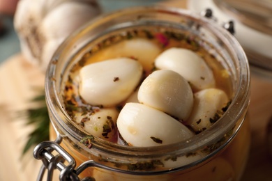 Photo of Aromatic preserved garlic in glass jar, closeup