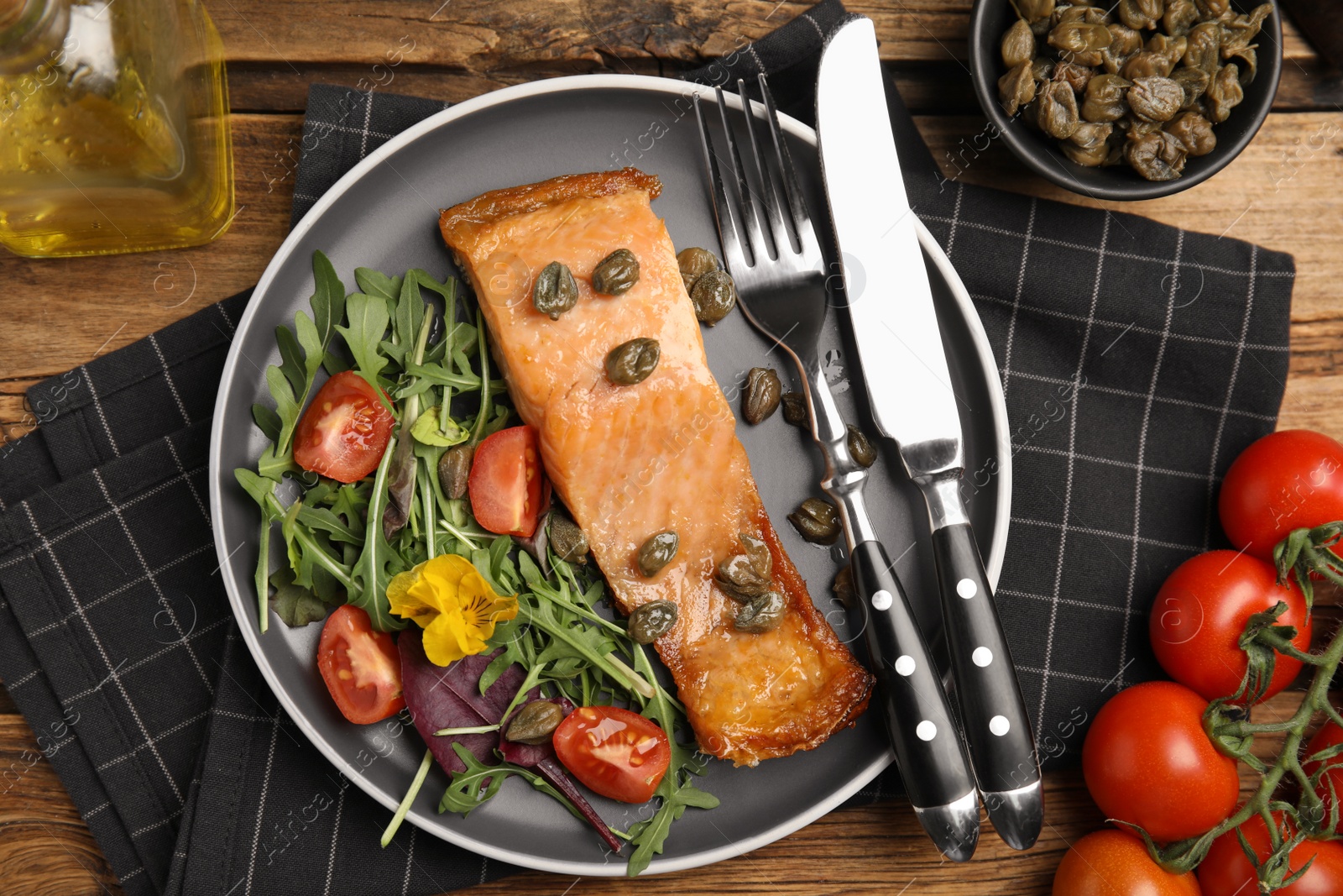 Photo of Tasty cooked salmon with capers and salad served on wooden table, flat lay