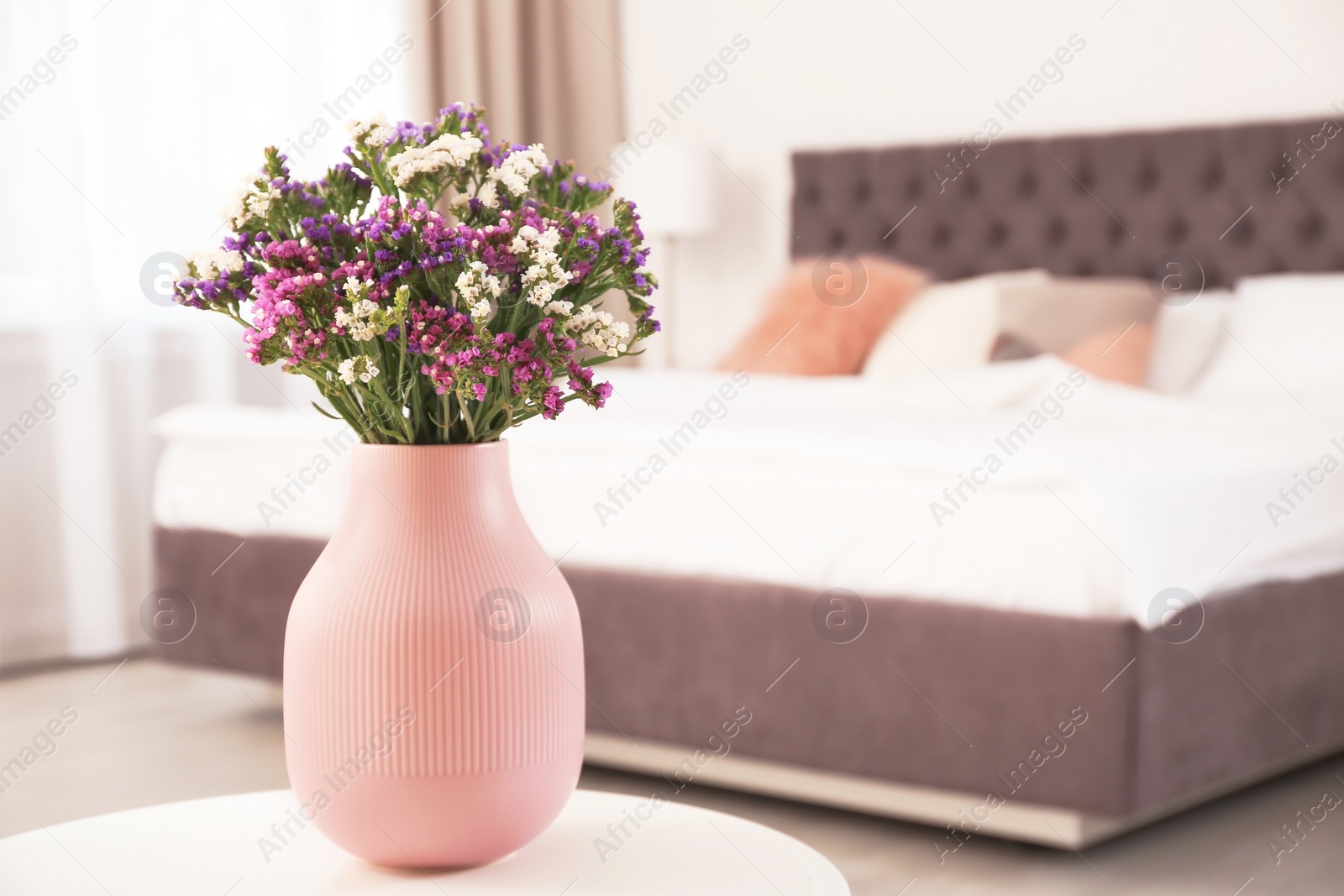 Photo of Beautiful flowers in vase and space for text on blurred background. Element of interior design