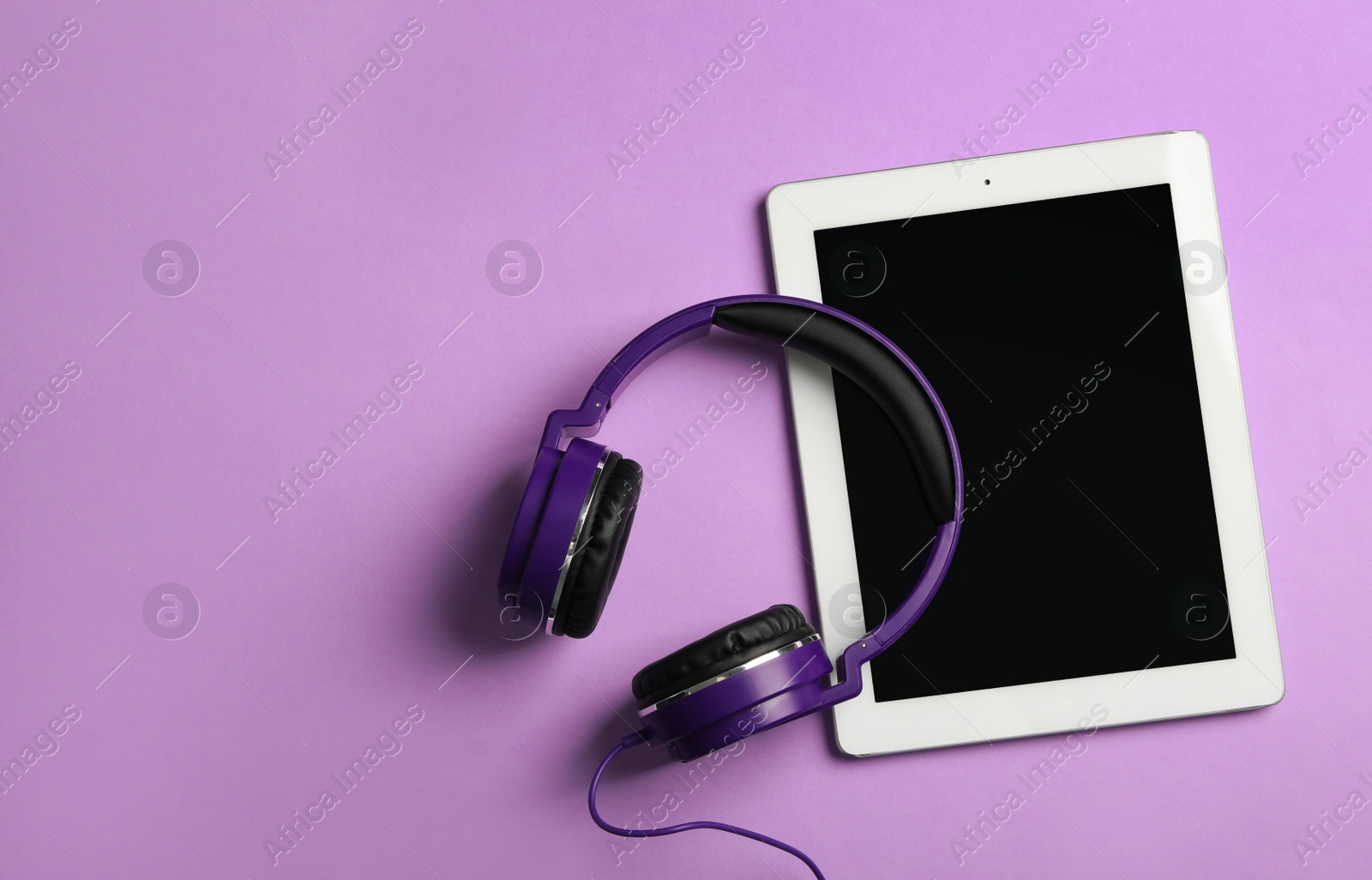 Photo of Stylish headphones and modern tablet on color background, flat lay. Space for text