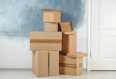 Photo of Pile of cardboard boxes near color wall indoors