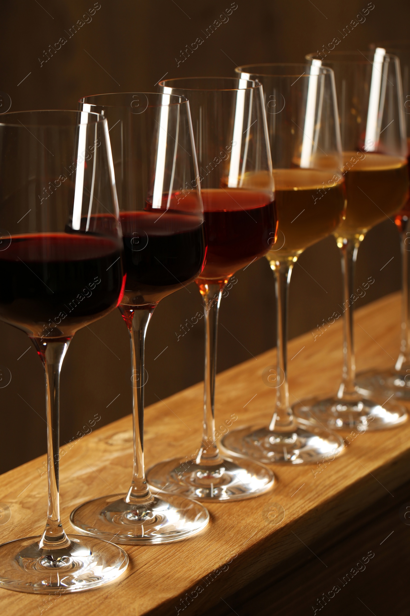 Photo of Glasses of different wines against blurred background. Expensive collection