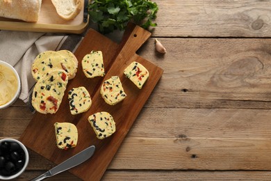 Photo of Tasty butter, olives, chili pepper, parsley and garlic on wooden table, top view. Space for text