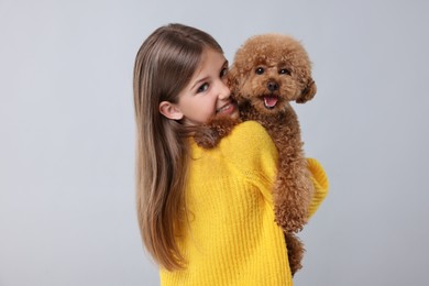 Photo of Little child with cute puppy on light grey background. Lovely pet