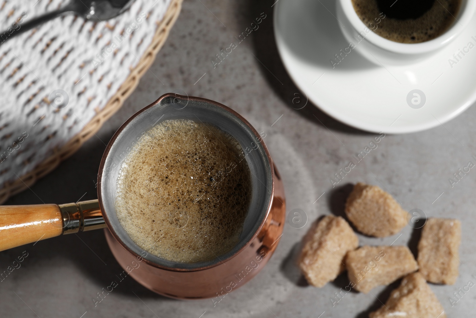 Photo of Turkish coffee. Cezve and cup with hot aromatic coffee and sugar on grey table, flat lay