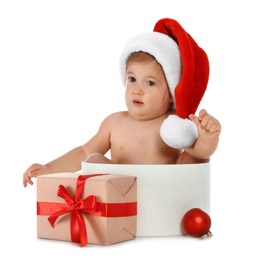 Cute little baby wearing Santa hat sitting in box with Christmas gift on white background
